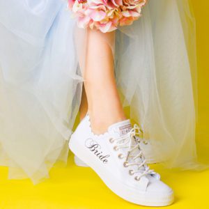 White trainer with scallapoed edge and bride on the side